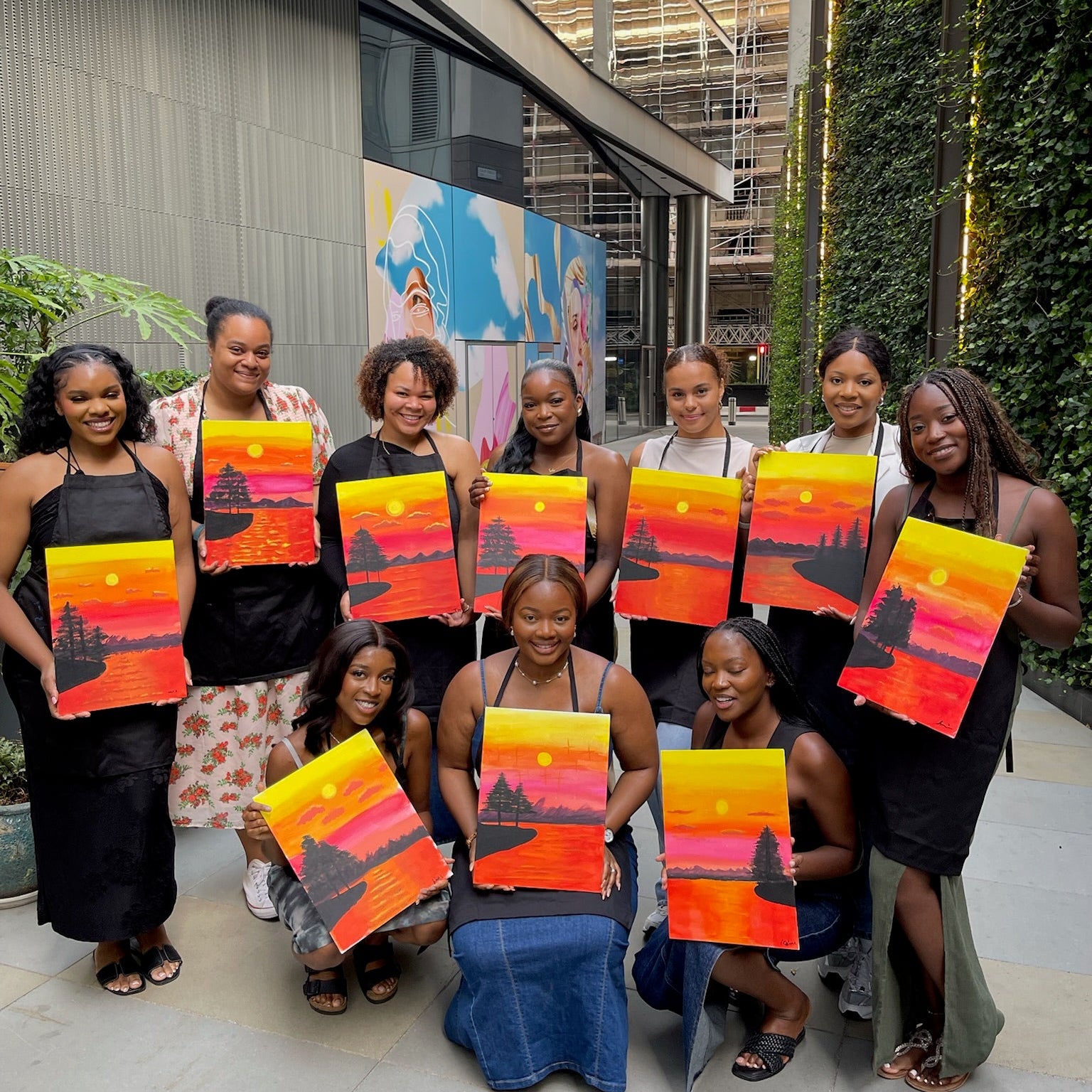 Group of women holding colorful paintings in an urban setting